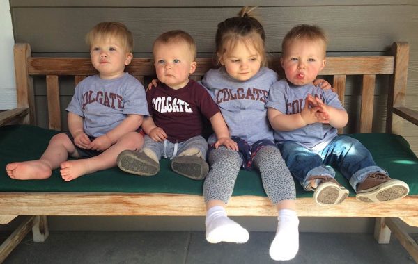Babies sitting on bench in Colgate t-shirts.