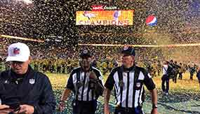 Two officials walk off the football field as confetti flies