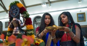 Two students in traditional attire hold a gold plate in the Hall of Presidents during Diwali, the Hindu festival of lights.